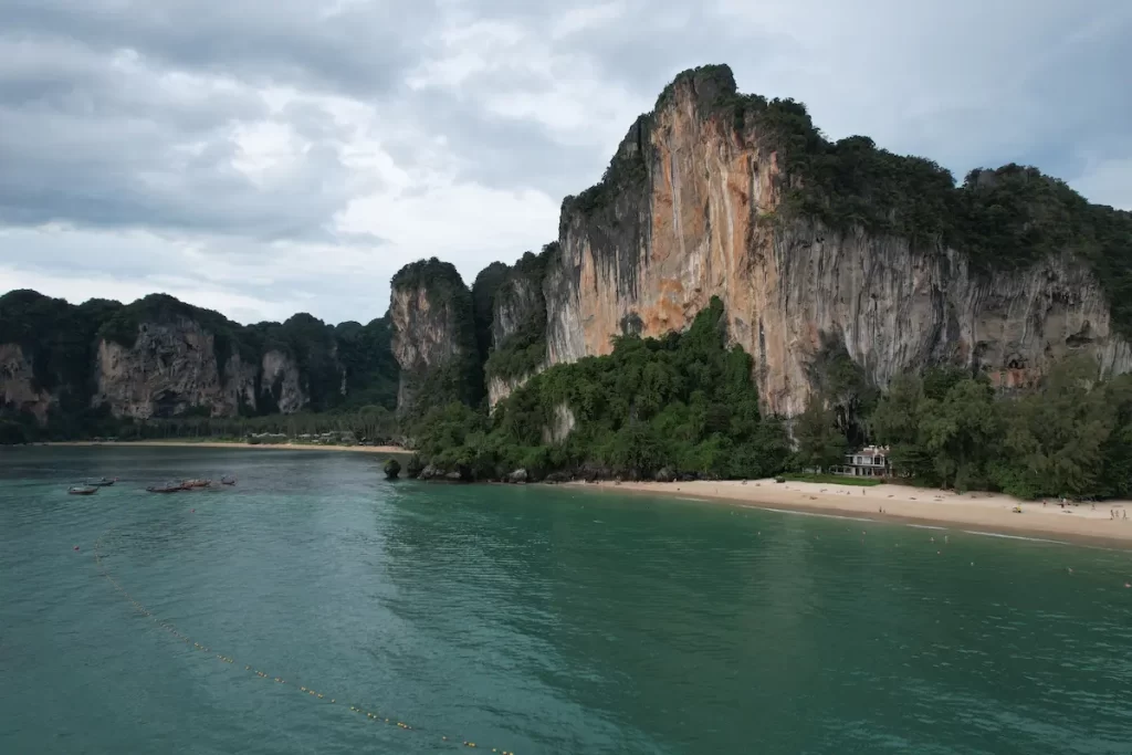 Must see attractions Thailand featuring the towering limestone cliffs and white sands of Railay Beach in Krabi.
