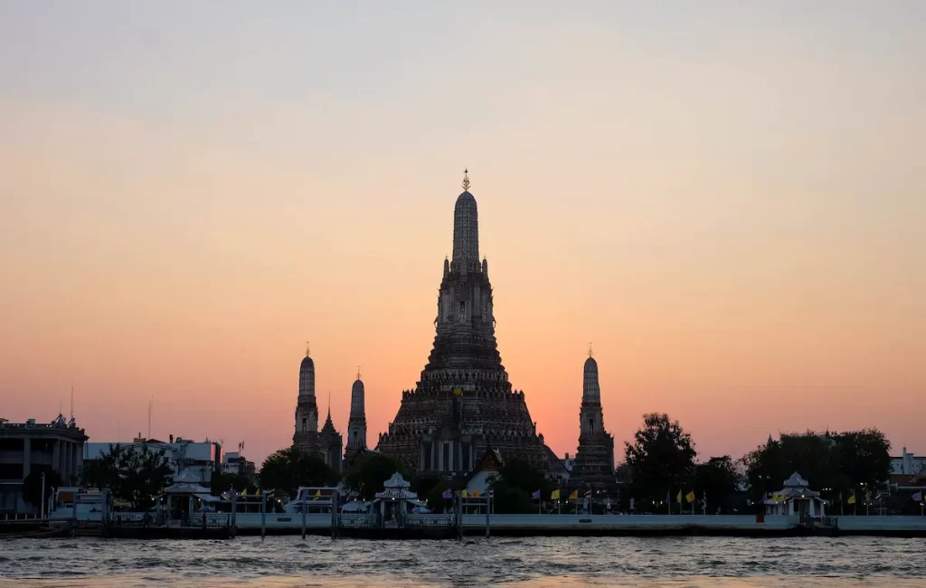 Must see attractions Thailand featuring Wat Arun, the iconic Temple of Dawn overlooking the Chao Phraya River in Bangkok.