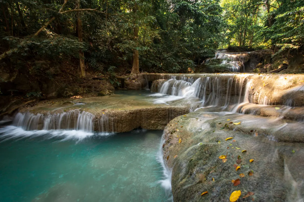 Multi-tiered waterfall surrounded by lush rainforest in Western Thailand, showcasing the region's spectacular national parks and natural beauty.