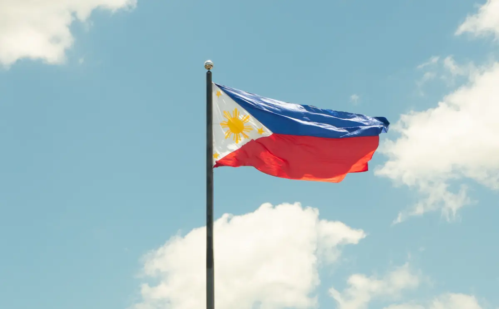 Philippine flag flying against a blue sky, representing the culture, identity and travel opportunities found throughout the Philippines.