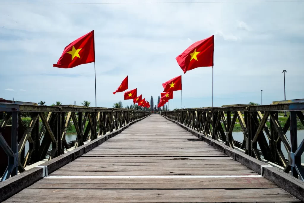 Vietnamese flags lining a wooden bridge in Vietnam, representing the country's culture, identity and sense of exploration for travellers.
