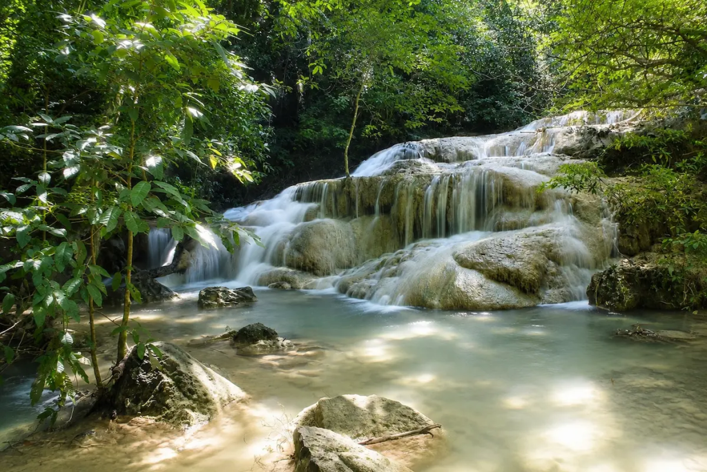 Beautiful Waterfalls In Thailand: Erawan Waterfall in Kanchanaburi featuring cascading limestone terraces and crystal-clear turquoise pools.