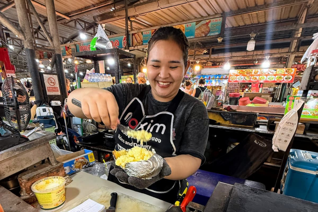 Smiling food vendor preparing a freshly made dish at Malin Plaza Patong.