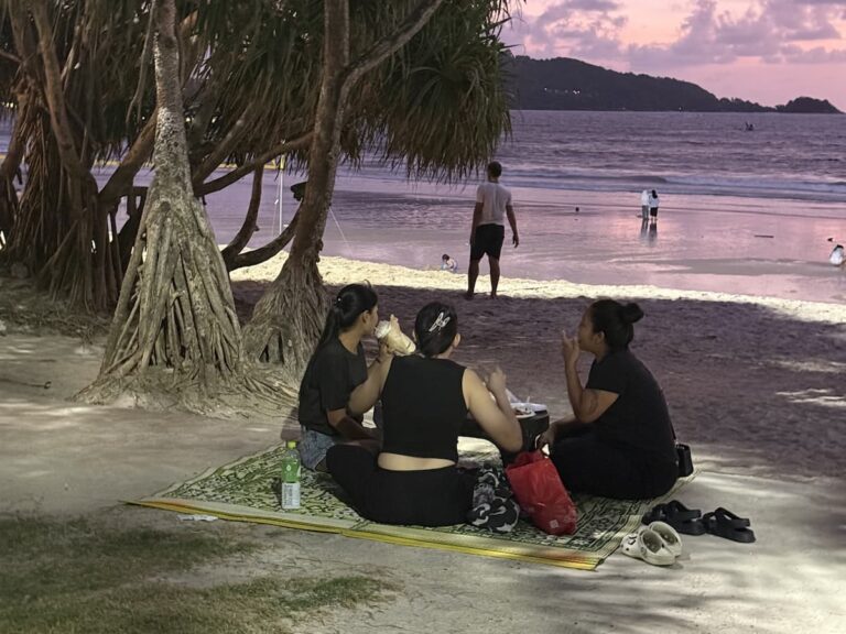 Thai families enjoying an evening picnic beneath the shade trees at Loma Park Patong overlooking Patong Beach.
