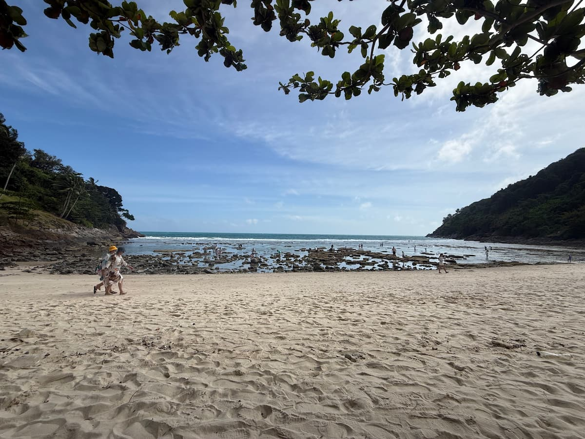 Merlin Beach in Phuket, showing the sandy bay, rocky reef and forested headlands