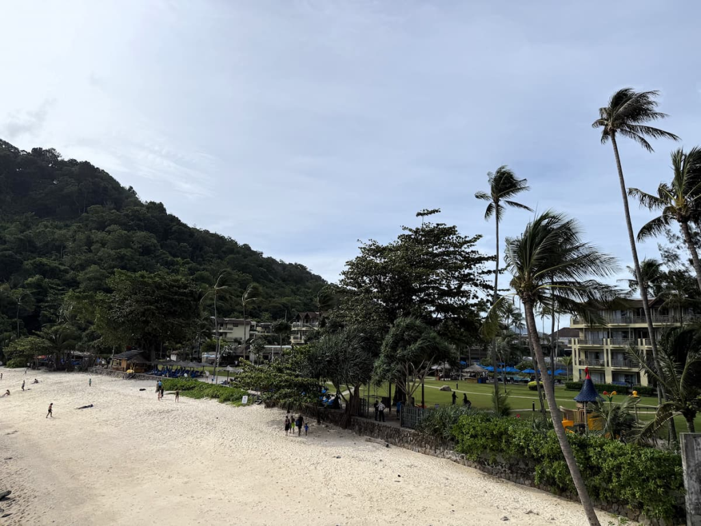 Merlin Beach with the beachfront resort and palm-lined grounds behind the public beach