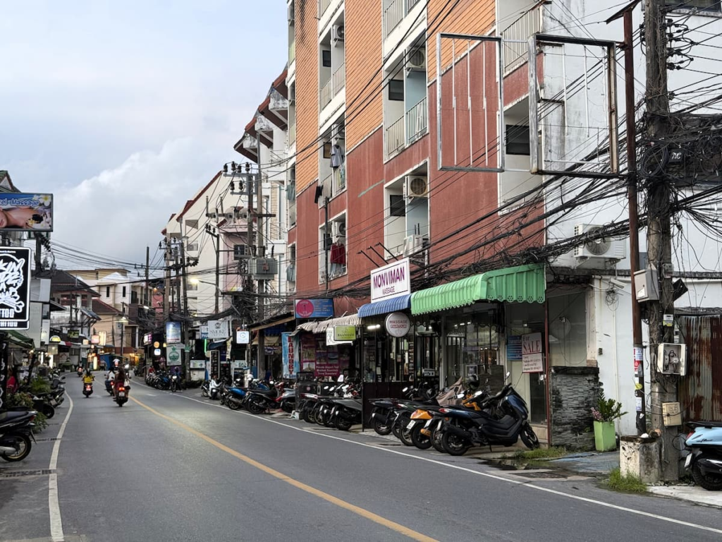 Quieter section of Nanai Road in Patong with guesthouses, massage shops and parked scooters