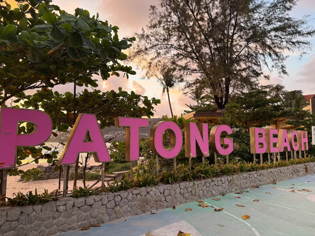 Visitors taking photos at the colourful Patong Beach sign along the beachfront featured in our Patong Travel Guide.