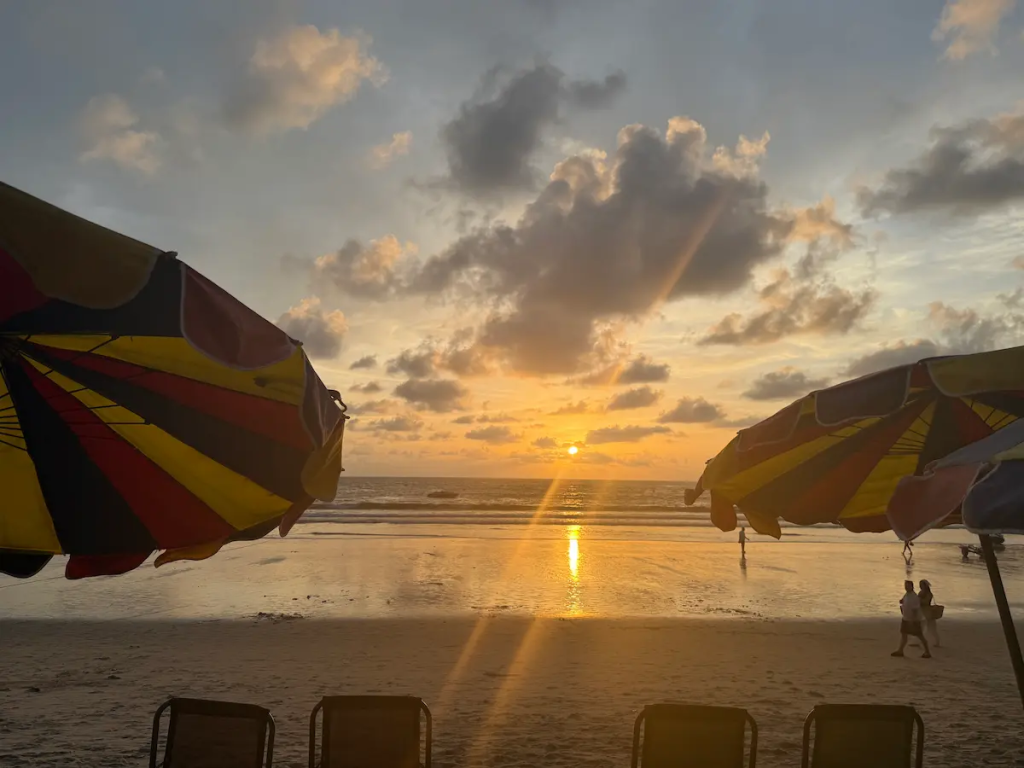 Sunset over Patong Beach between colourful umbrellas, showing why visit Patong is a popular question for Phuket travellers.