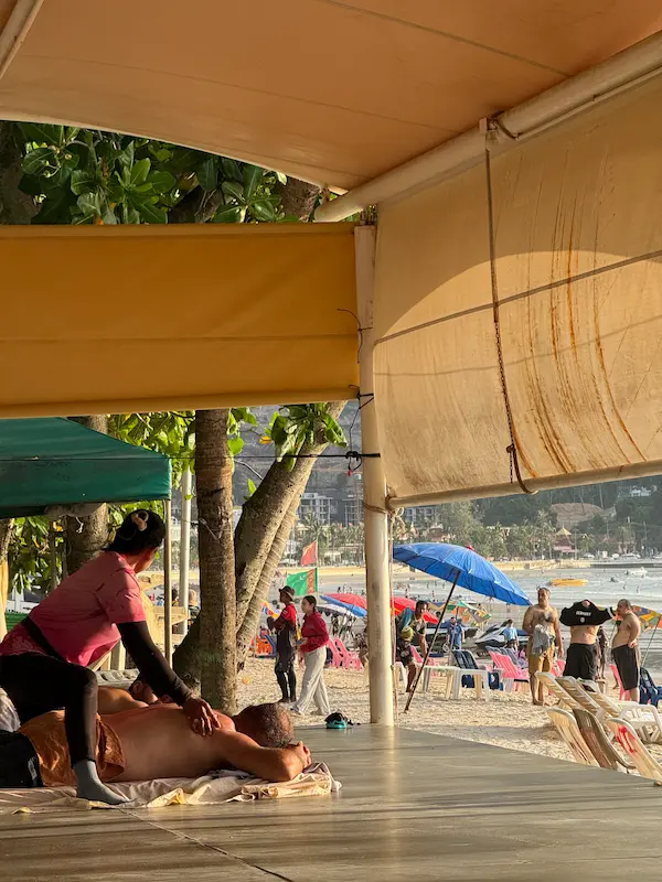 Traditional Thai massage being enjoyed at a licensed beachfront massage area in our Patong Travel Guide.