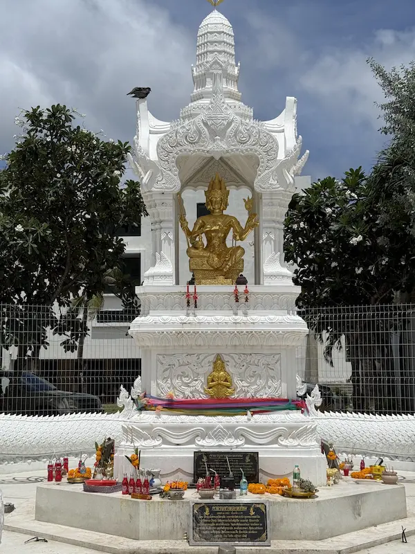 Front view of the Patong Phra Phrom Shrine in Phuket with the golden four-faced Brahma statue, offerings and traditional Thai shrine architecture.