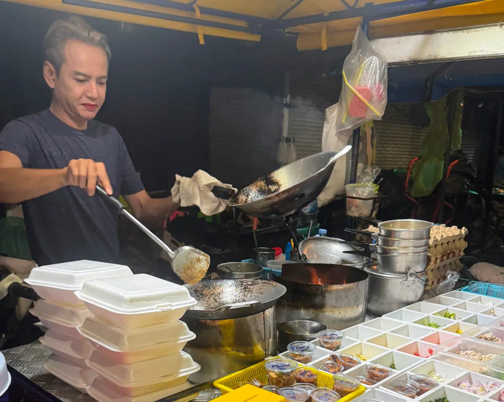Street food vendor preparing fresh Thai food at a market stall in Patong