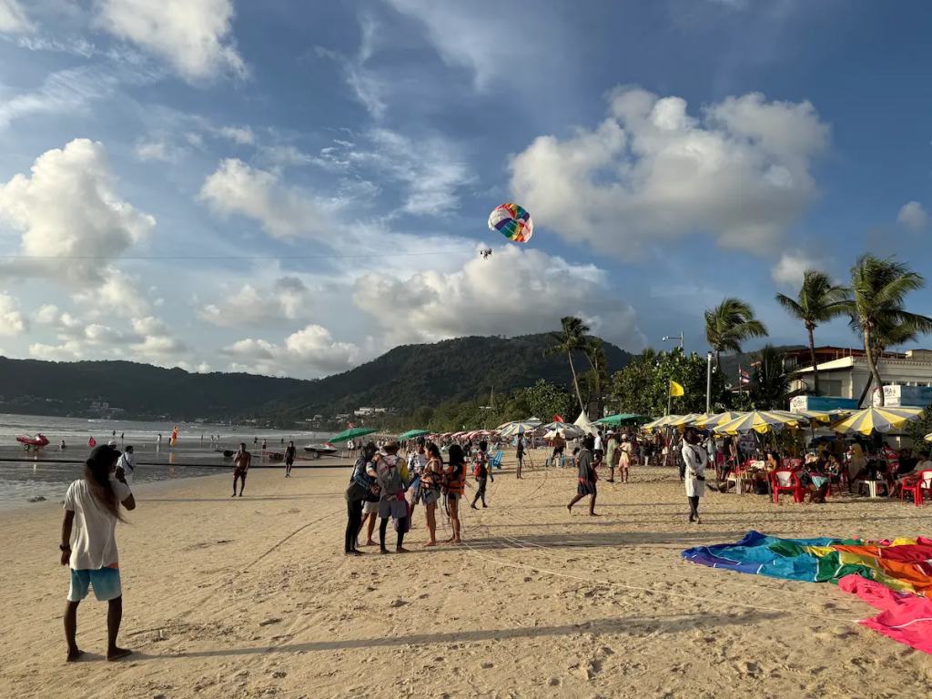 Visitors enjoying parasailing and other water activities on Patong Beach, Phuket.