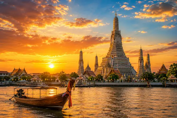 Southeast Asia destination featuring a traditional Thai longtail boat and riverside temple at sunset, representing the culture, landscapes and travel experiences of the region.