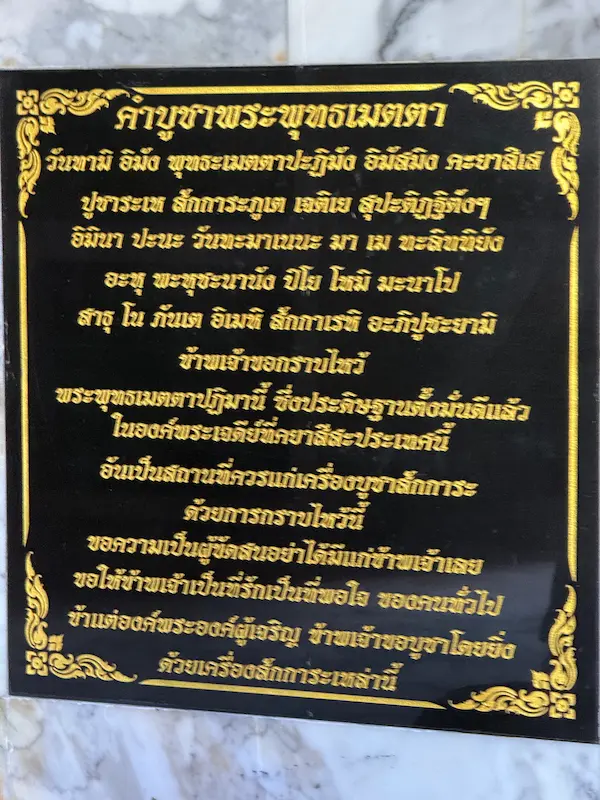 Thai prayer plaque dedicated to the Buddha of Loving-Kindness inside the sacred chedi at Wat Doi Thep Nimit in Phuket.
