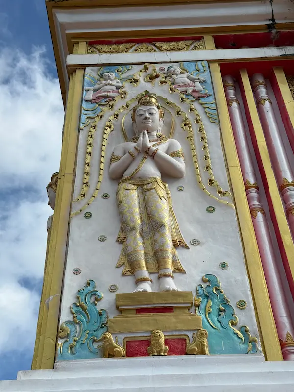 Decorative celestial relief panel on the exterior of the Phra Maha Chedi at Wat Doi Thep Nimit in Phuket.