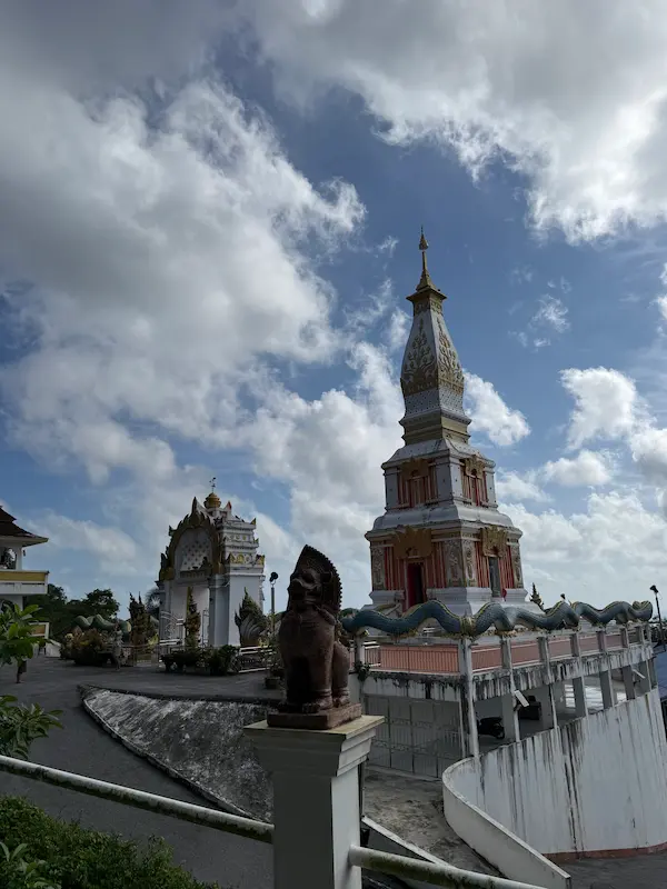 The Phra Maha Chedi and surrounding temple grounds at Wat Doi Thep Nimit in Phuket, showing the naga-lined platform and hillside setting.