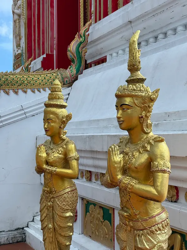 Guardian deva statues standing beside the entrance to the Phra Maha Chedi at Wat Doi Thep Nimit in Phuket.
