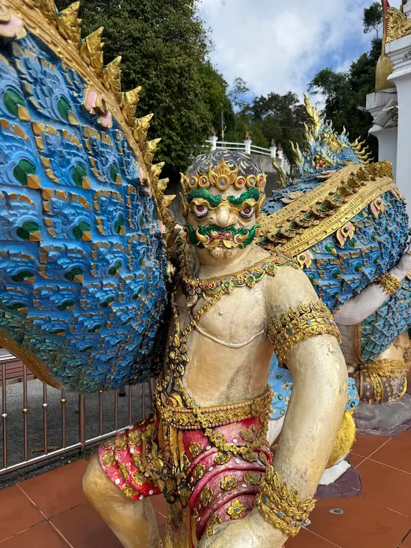 Guardian Yaksha statue protecting the sacred chedi at Wat Doi Thep Nimit in Phuket.