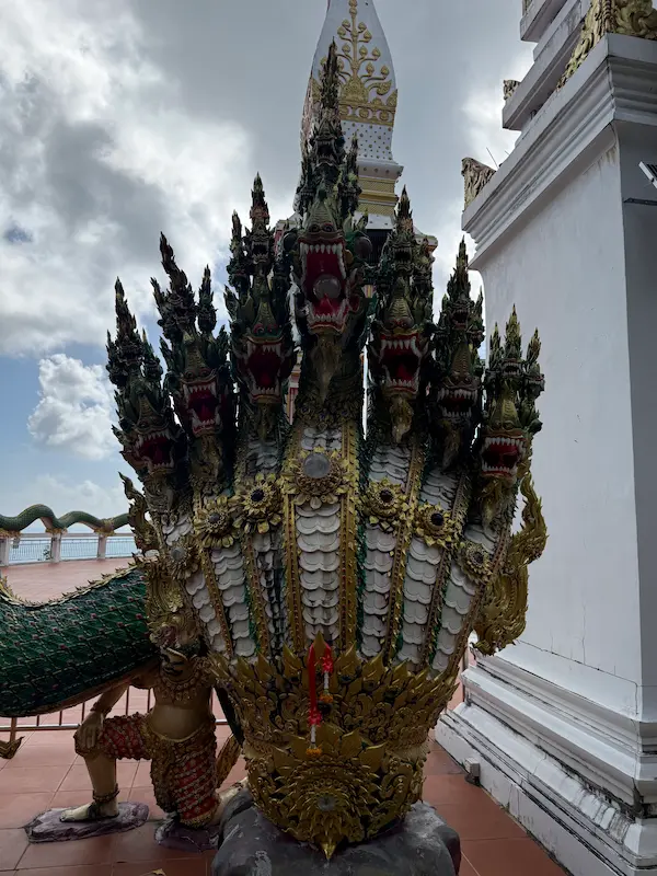 Seven-headed naga guardian surrounding the Phra Maha Chedi terrace at Wat Doi Thep Nimit in Phuket.