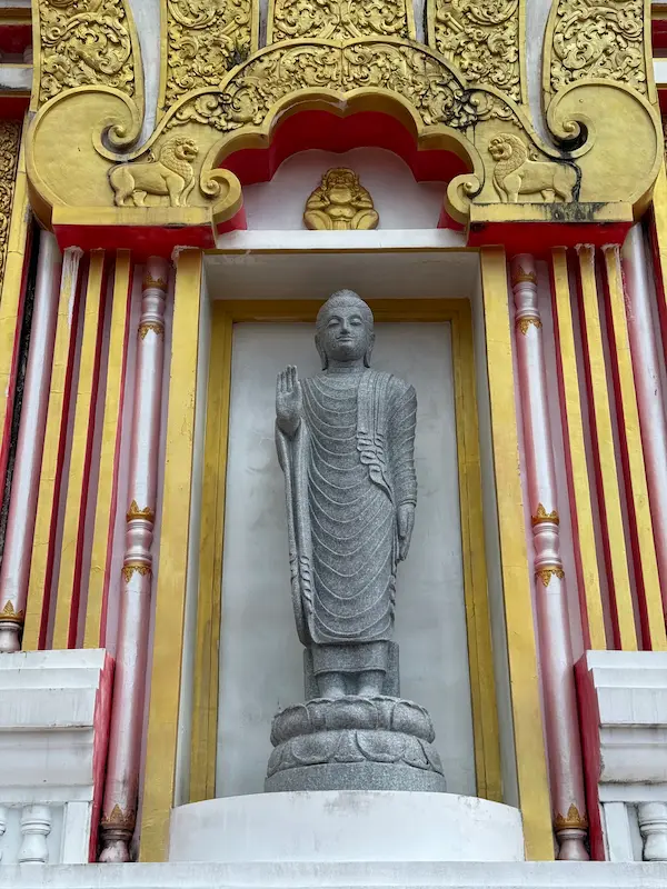 Standing Buddha image set into the exterior wall of the Phra Maha Chedi at Wat Doi Thep Nimit in Phuket.