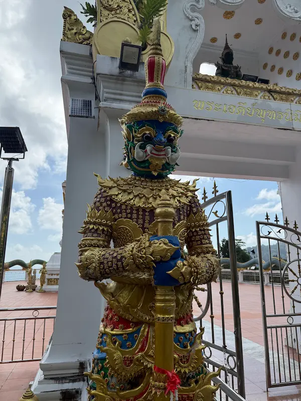 Yaksha guardian statue holding a ceremonial club at the gateway to the Phra Maha Chedi at Wat Doi Thep Nimit in Phuket.