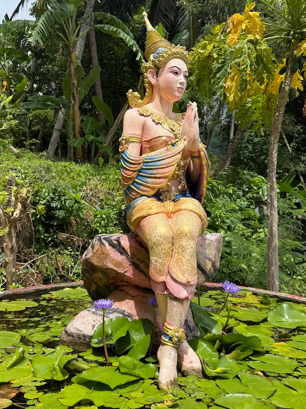 Seated devata statue beside the naga staircase at Wat Suwan Khiri Wong Patong