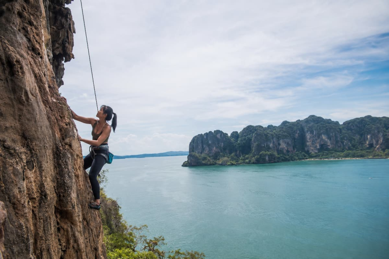 Rock climber ascending a limestone cliff at Railay, featured among the best adventure activities in Southern Thailand.
