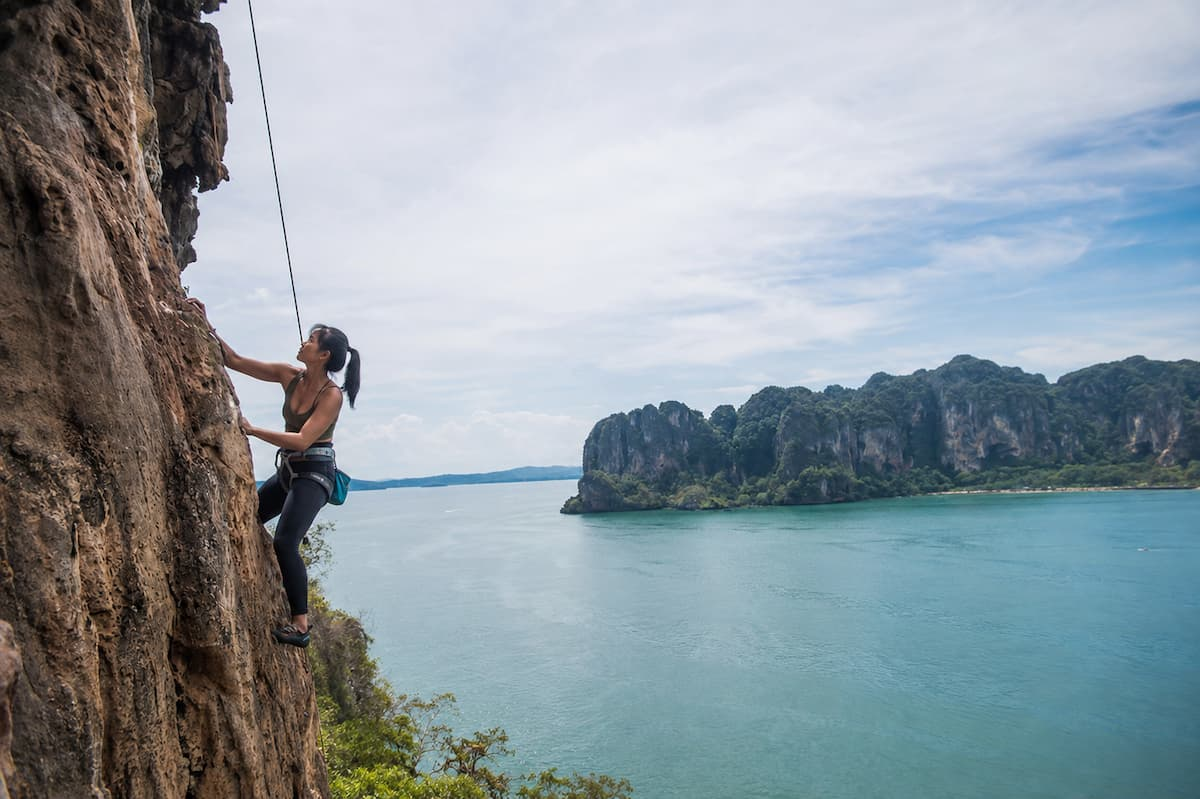 Rock climber ascending a limestone cliff at Railay, featured among the best adventure activities in Southern Thailand.