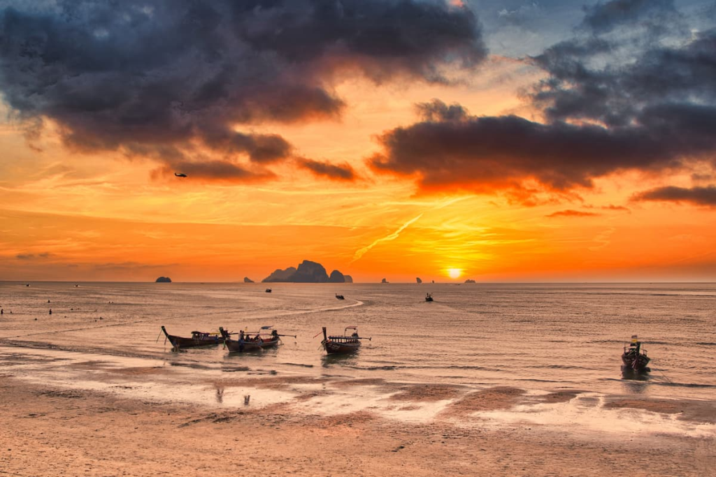 Longtail boats at sunset on the Andaman Coast during the best time to visit Southern Thailand.