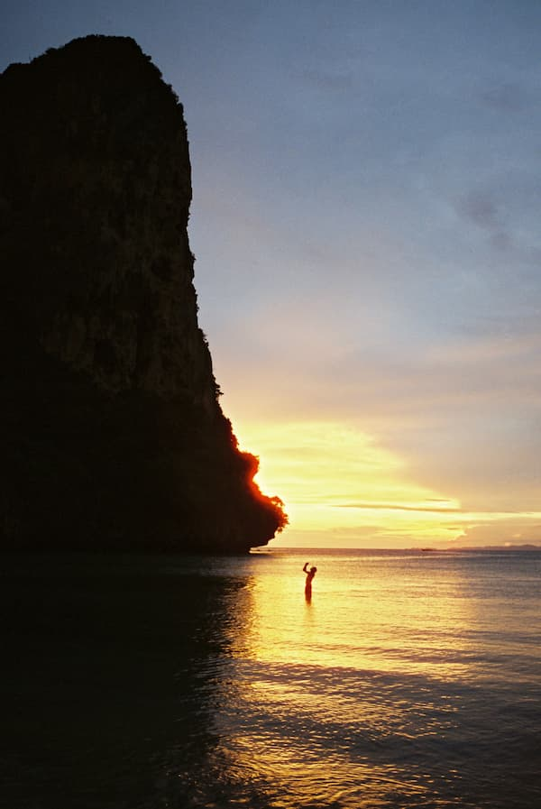Limestone cliff and person silhouetted at sunset in Ao Nang, featured in a Southern Thailand travel guide.