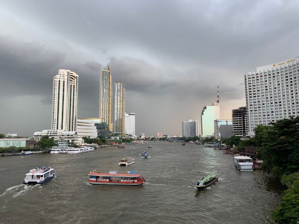 Bangkok skyline and passenger boats on the Chao Phraya River in a guide to where to go in Central Thailand.