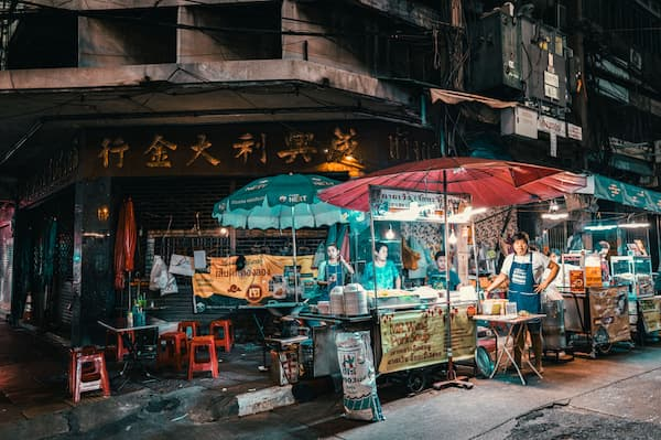 Street food vendors serving customers beneath colourful umbrellas in Bangkok’s Chinatown