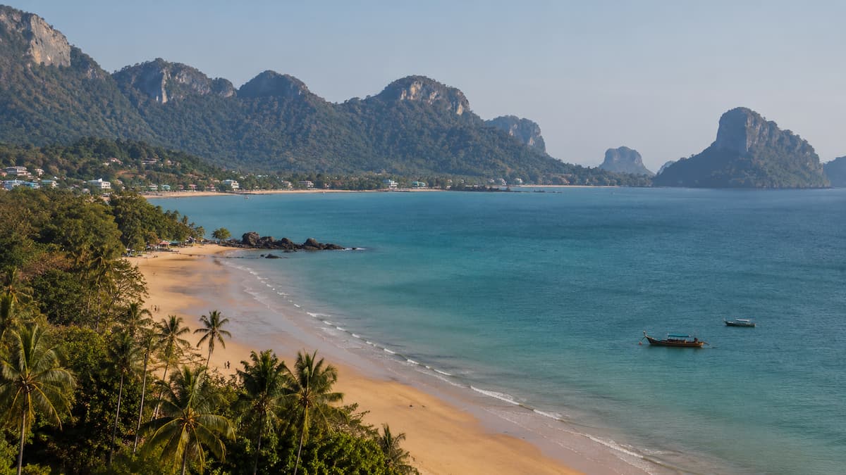 Best places in Thailand for different types of holiday, with a tropical beach, longtail boats and forested limestone mountains.