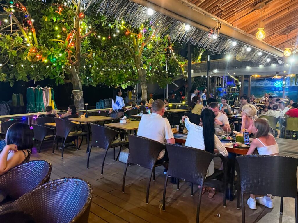 Visitors enjoying beachfront dining at Blue Beach in Patong during the evening with live music and a relaxed atmosphere.