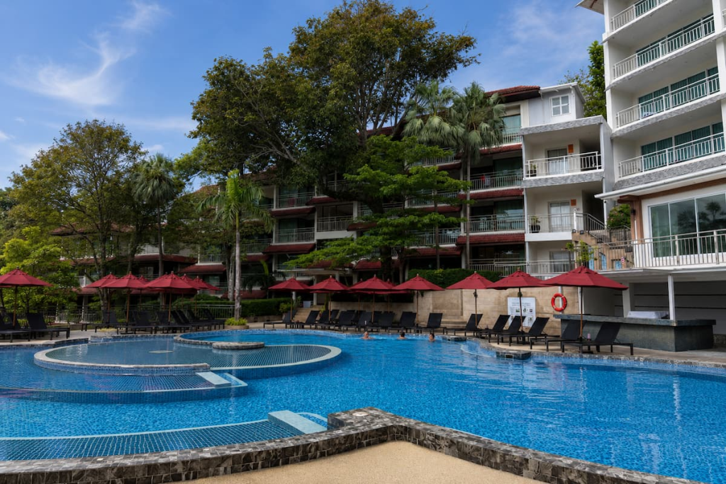 Swimming pool, red parasols and balcony rooms at Chanalai Flora Resort in Kata, featured in our Phuket travel guide.