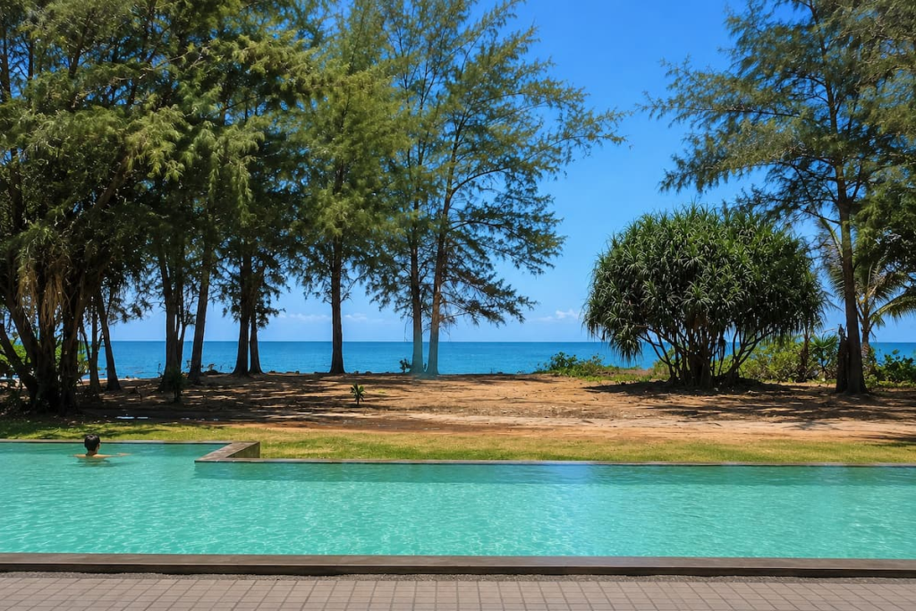 Pool overlooking trees and the sea at Coriacea Boutique Resort in Mai Khao, featured in our Phuket travel guide.