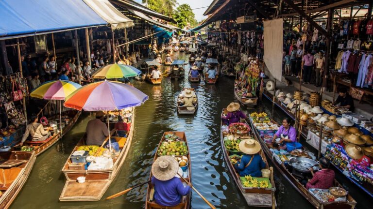 Floating markets in Thailand with wooden boats, food vendors and market stalls along a busy canal