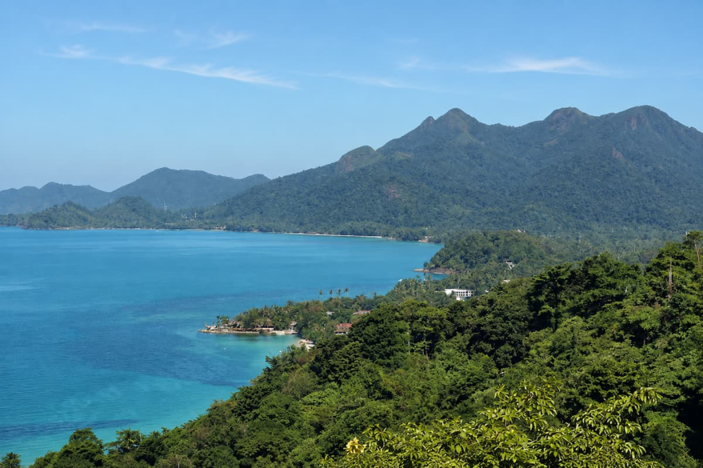Thailand travel guide view across Koh Chang’s turquoise coastline towards its densely forested mountain interior.