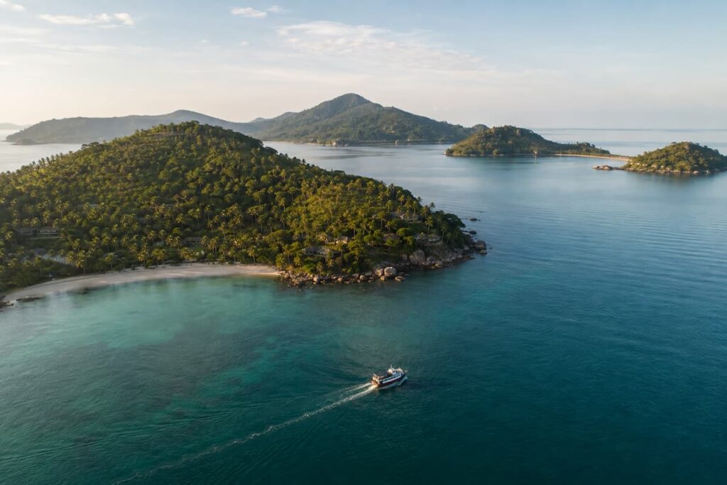 Passenger boat travelling between forested islands in Southern Thailand’s Gulf coast