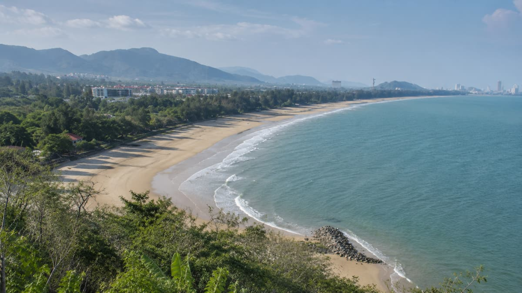 Thailand travel guide view across Hua Hin’s sweeping sandy coastline, blue Gulf waters and surrounding mountains.