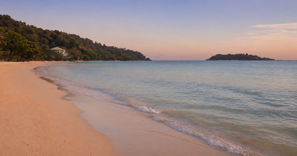 Thailand travel guide view along Kai Bae Beach towards a forested island off the coast of Koh Chang at sunset.