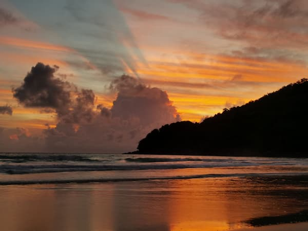 Sunset reflecting across the sand and water at Karon Beach, one of the best beaches in Phuket for long walks.
