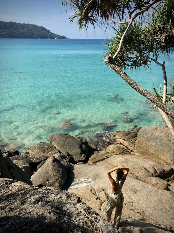 Rocky shoreline and clear turquoise water in Karon, Phuket, featured in our Karon travel Guide.