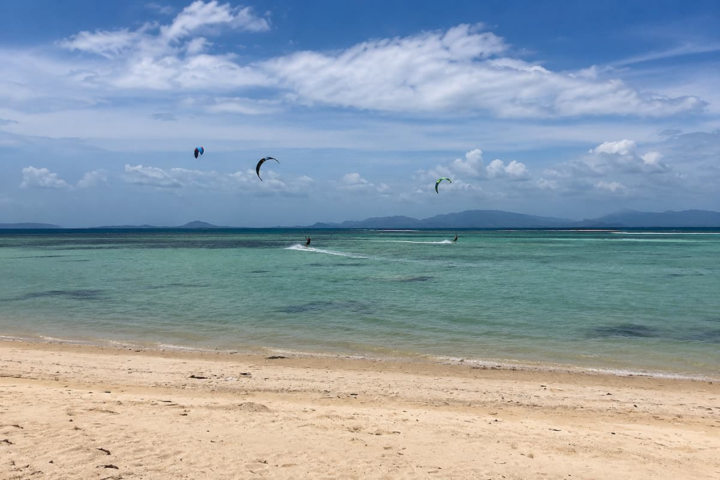 Kitesurfers riding across shallow water at Koh Phangan, an adventure activity in Southern Thailand.