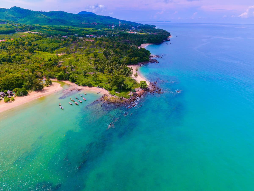 Aerial view of Koh Lanta coastline and longtail boats on an island-hopping route through Southern Thailand.