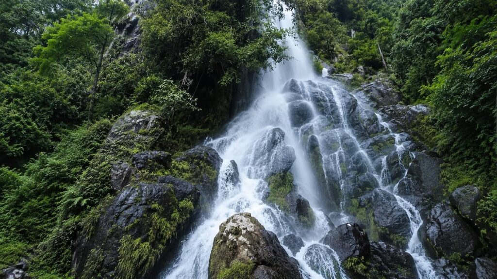Krok E Dok Waterfall flowing over forested rocks in Saraburi, featured in where to go in Central Thailand.