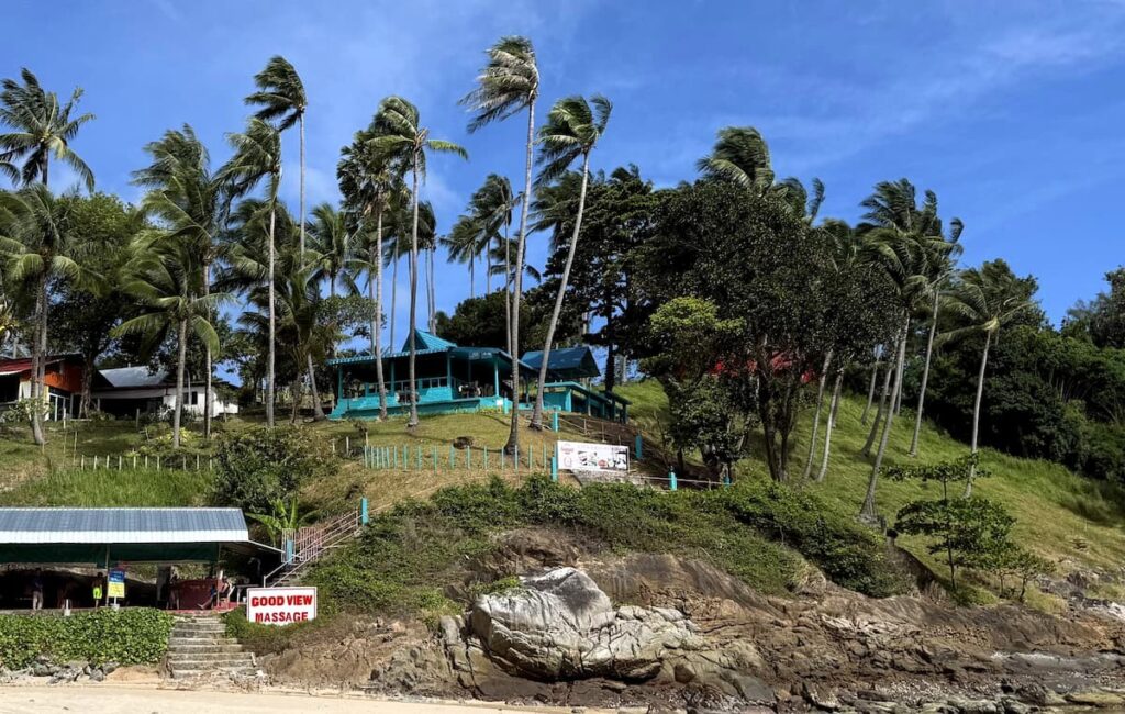 Little Tiger Restaurant in Patong on the hillside above Merlin Beach, surrounded by tropical palm trees.