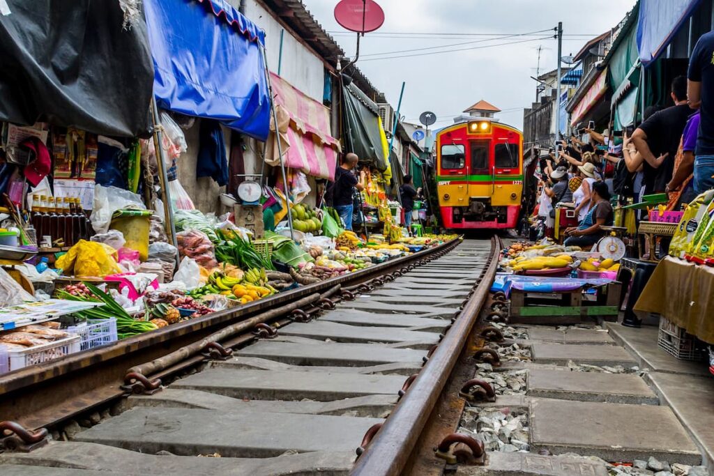 Train passing through Mae Klong Railway Market in Samut Songkhram, featured in where to go in Central Thailand.