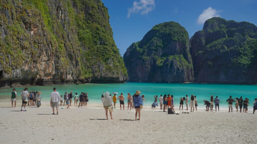 Visitors along the shoreline of Maya Bay beneath limestone cliffs on Phi Phi Leh